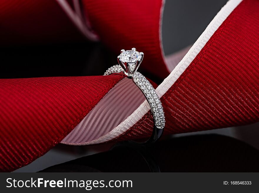 Wedding diamonds ring on black background with red ribbon