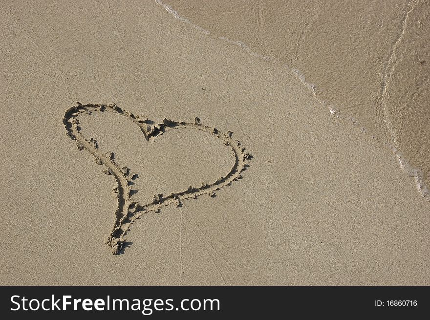 A heart drawn in the sand by the waters edge. A heart drawn in the sand by the waters edge.