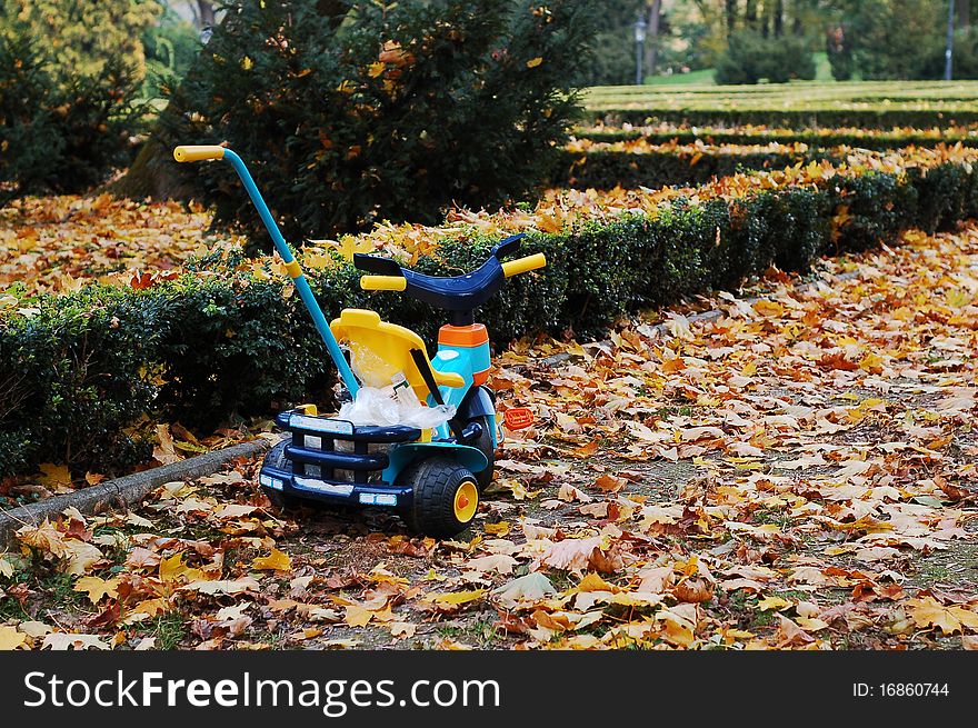 Plastic children tricycle in the autumn park in the fallen leaves