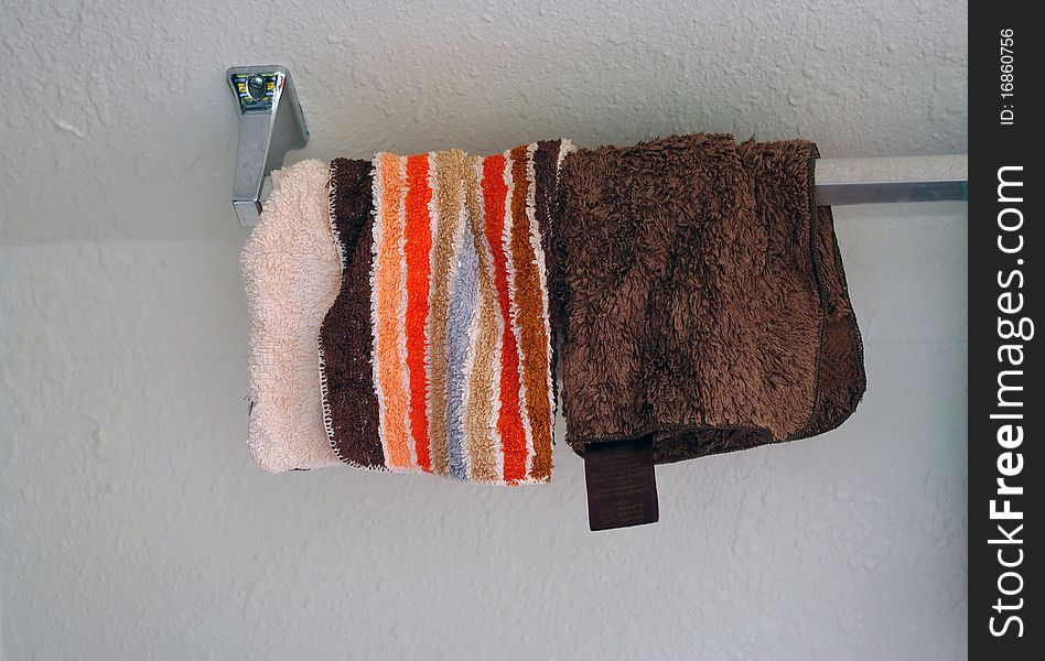 A couple used washrags hanging from a towel rack. A couple used washrags hanging from a towel rack