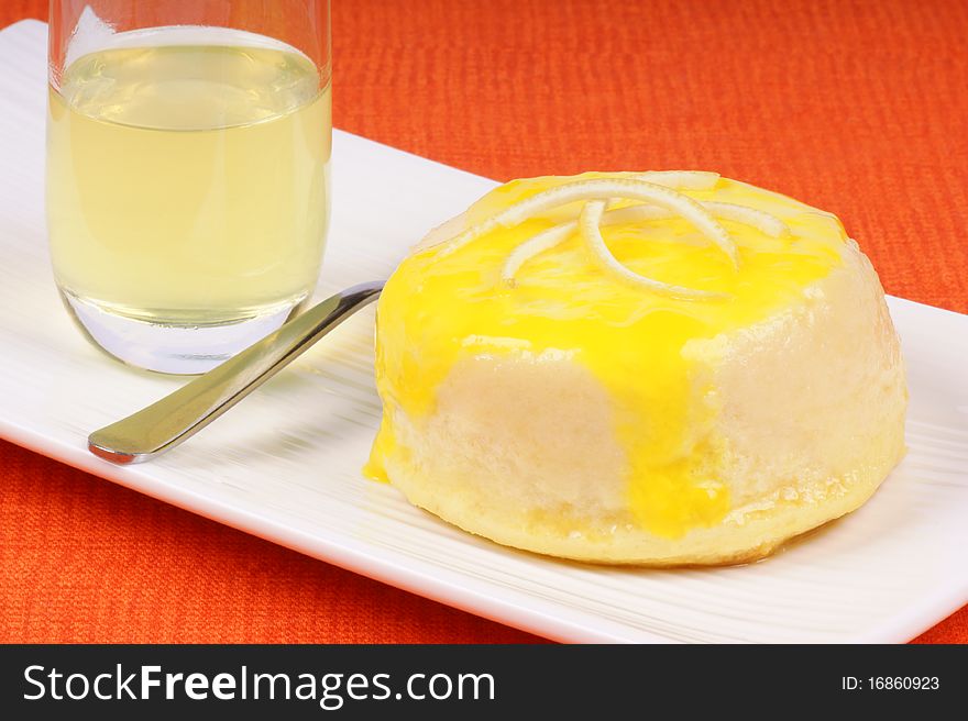 Lemon and ricotta souffle with a small glass of limoncello and a teaspoon on a white plate