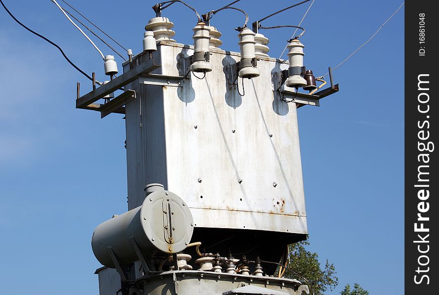 The electric transformer substation against a blue sky