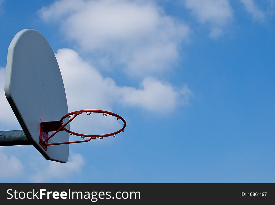 An empty basketball hoop against a bright blue sky, with large clouds drifting from behind the backboard. An empty basketball hoop against a bright blue sky, with large clouds drifting from behind the backboard.