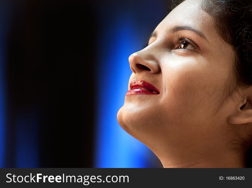 High contrast, portrait of a smiling young Indian woman. Blue light background. High contrast, portrait of a smiling young Indian woman. Blue light background