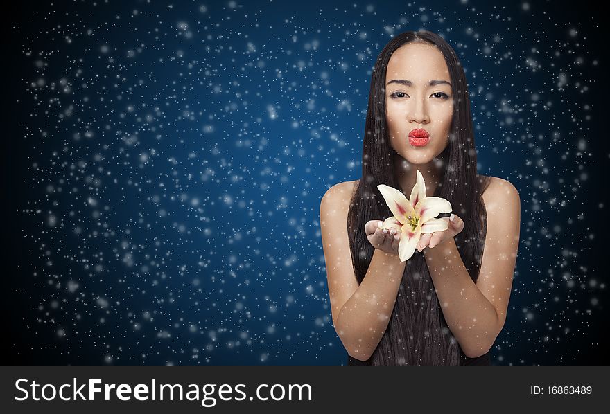 Beautiful girl holding lily with snow blured around on the blue background. Beautiful girl holding lily with snow blured around on the blue background