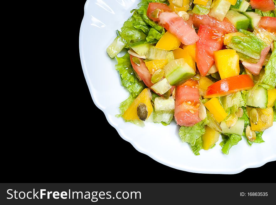 Salad with tomato, pepper, pumpkin seeds on the white plate isolated