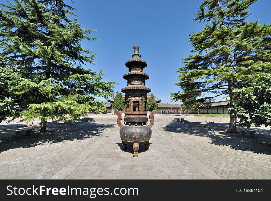An old censer in Chinese temple courtyard in wide view angle, surround with traditional architecture and trees in radial and symmetrical. An old censer in Chinese temple courtyard in wide view angle, surround with traditional architecture and trees in radial and symmetrical.