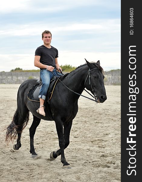 Young man and his black stallion on the beach. Young man and his black stallion on the beach