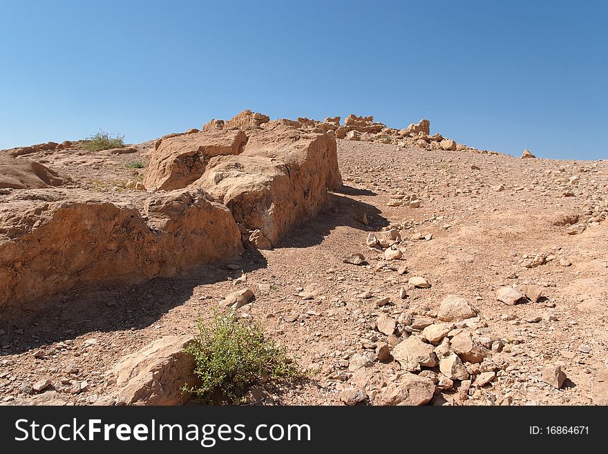 Ruined wall of ancient fortress in the orange desert