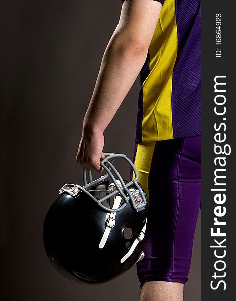 Athlete holding football helmet is studio