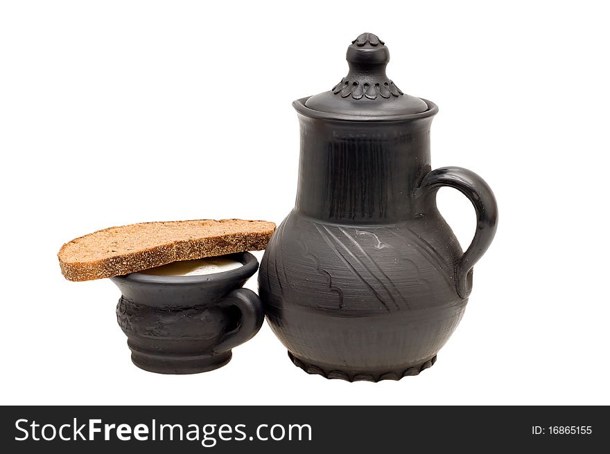 Milk in the cup, pitcher made of black clay and rye bread with caraway on a white background. Milk in the cup, pitcher made of black clay and rye bread with caraway on a white background