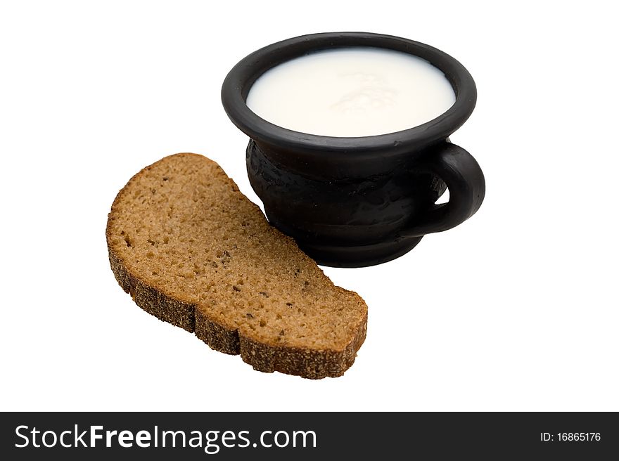 Milk in the cup made of black clay and rye bread with caraway on a white background. Milk in the cup made of black clay and rye bread with caraway on a white background