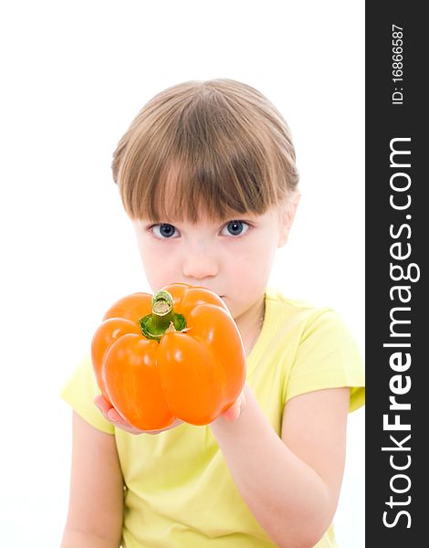 The portrait of a cute little girl looking at the camera and holding a pepper