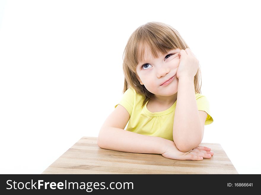 The portrait of a clever little girl sitting at the table