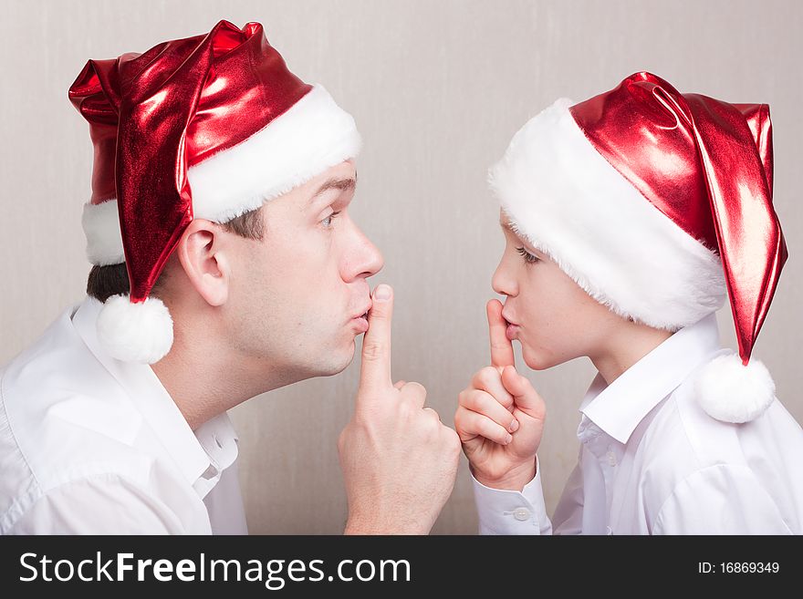 Father and son in santa hat showing silence sign. Father and son in santa hat showing silence sign.