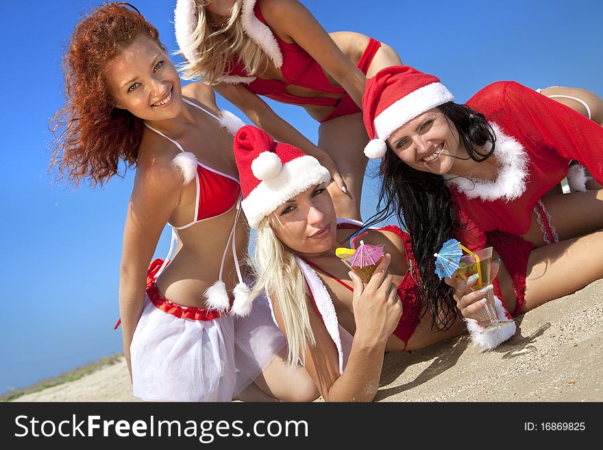 Four young beautiful women in christmas suit with martini glass on the beachfront. Four young beautiful women in christmas suit with martini glass on the beachfront