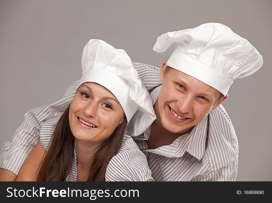 Young loving couple cooks. Over gray background