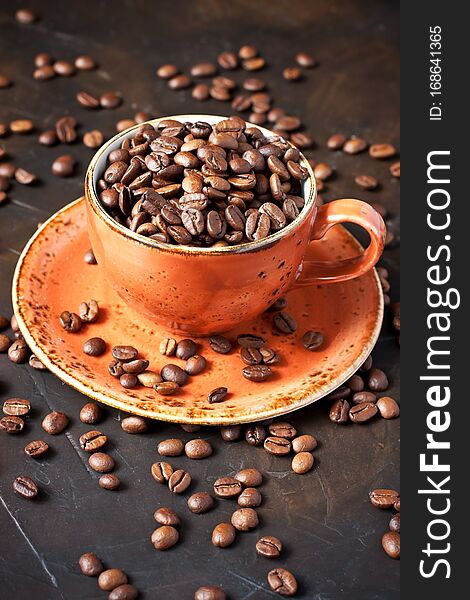 Food  background  with  black roasted coffee beans in ceramic mug, selective  focus with  shallow depth of field. Food  background  with  black roasted coffee beans in ceramic mug, selective  focus with  shallow depth of field