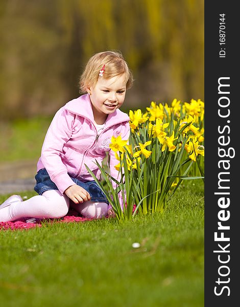 Little Girl And Daffodils In Park.