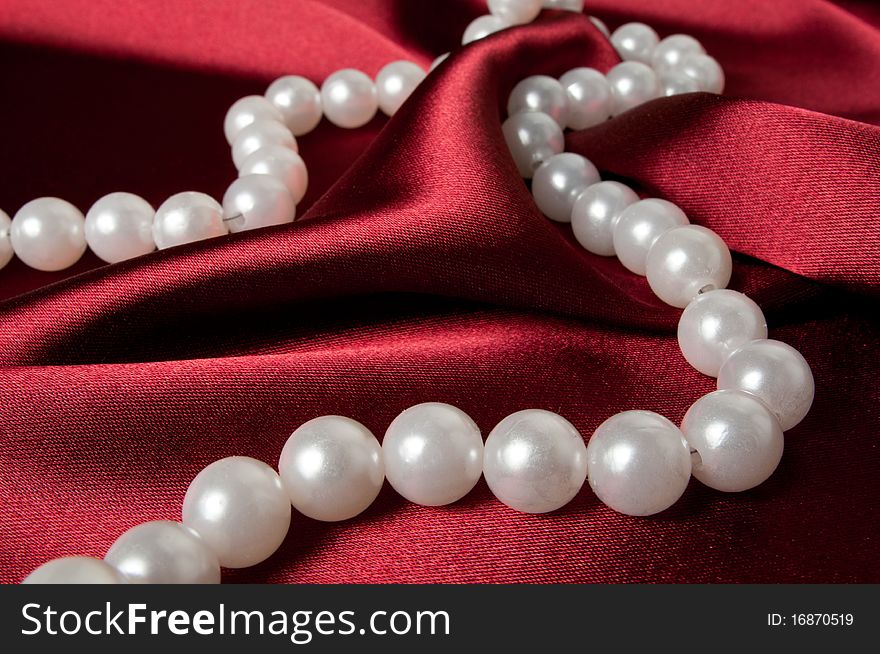 A pearl necklace on red satin. A pearl necklace on red satin