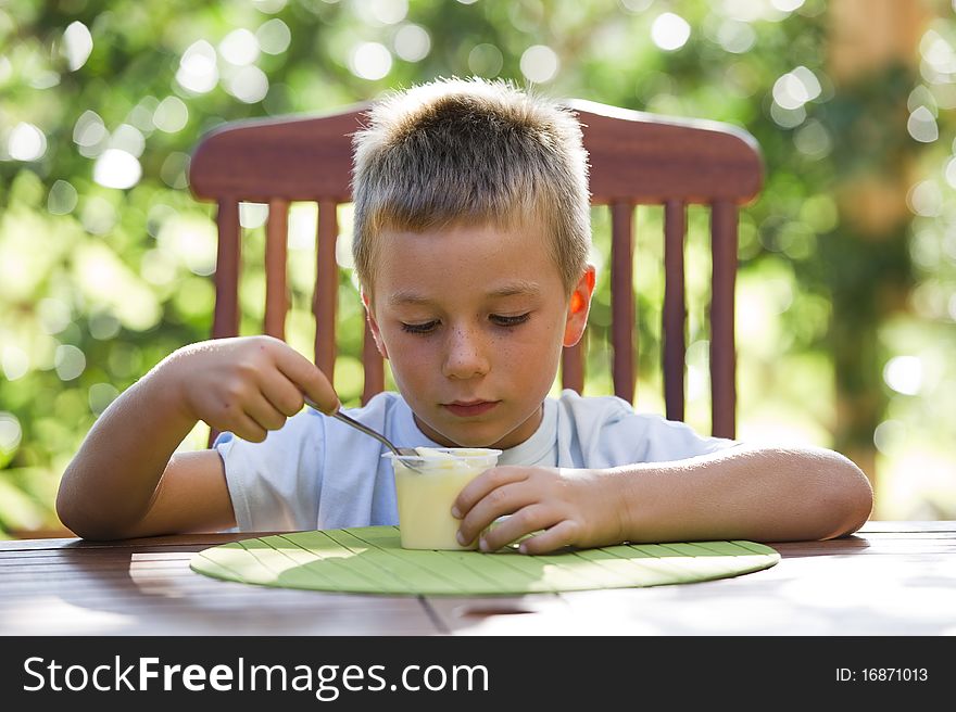 Cute little boy eating oudding outside. Cute little boy eating oudding outside