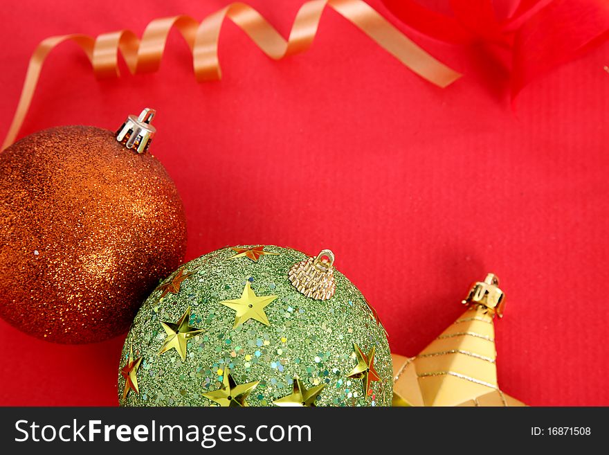 Gold Christmas star, colors ball and gold ribbon over red background