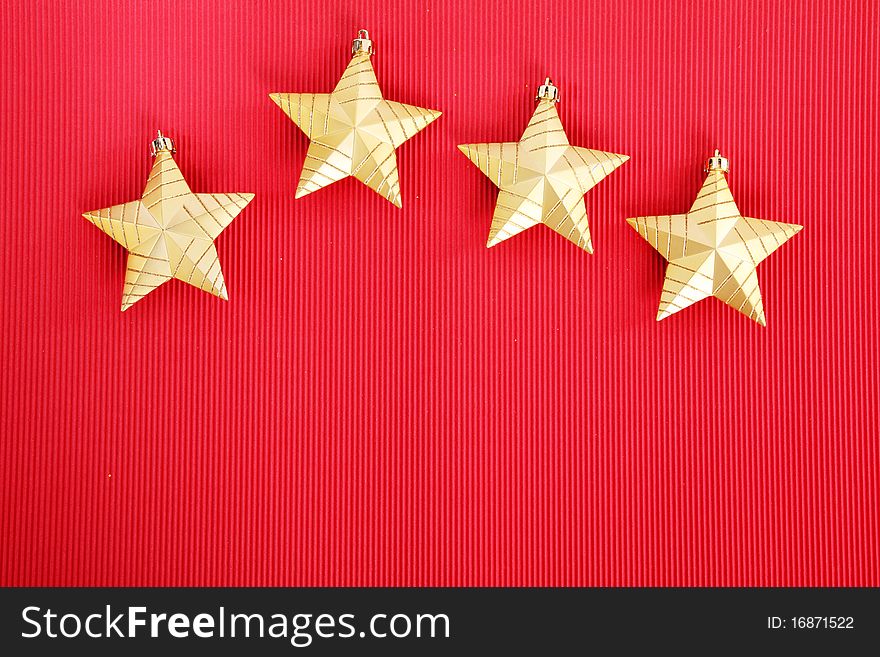 Four gold Christmas stars over red background