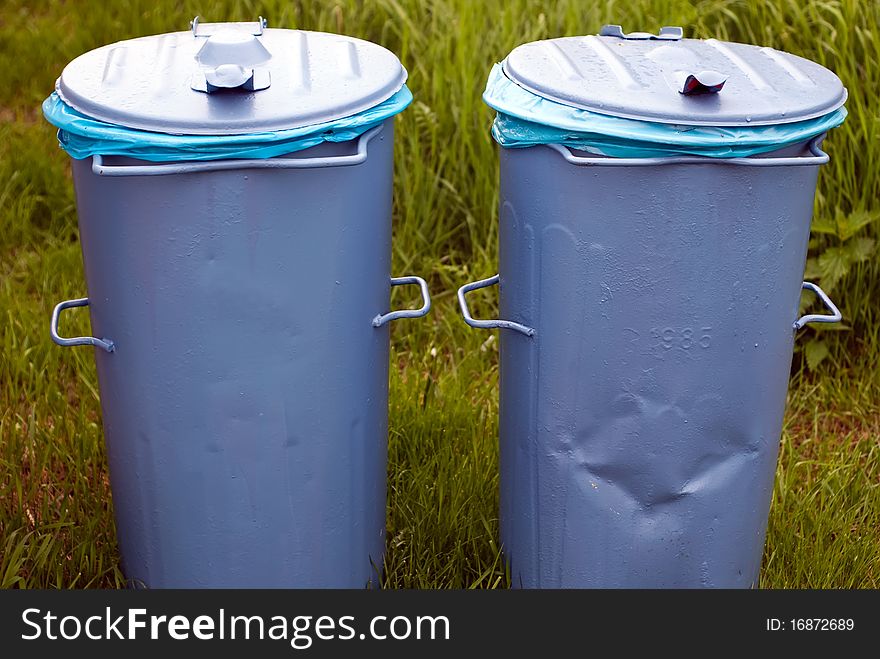 Two blue bins standing in a green meadow. Two blue bins standing in a green meadow