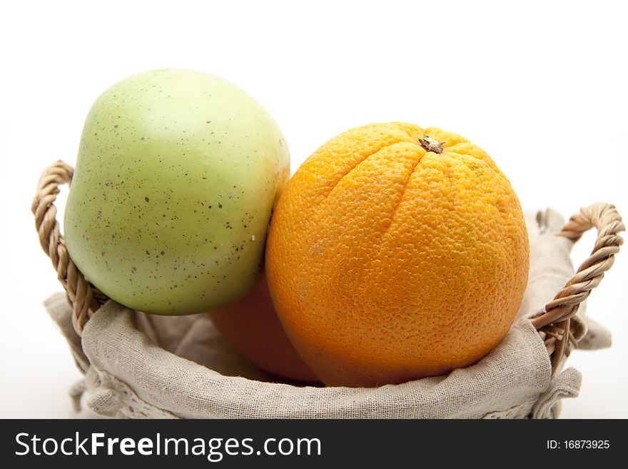 Oranges and apple in the basket with material coating