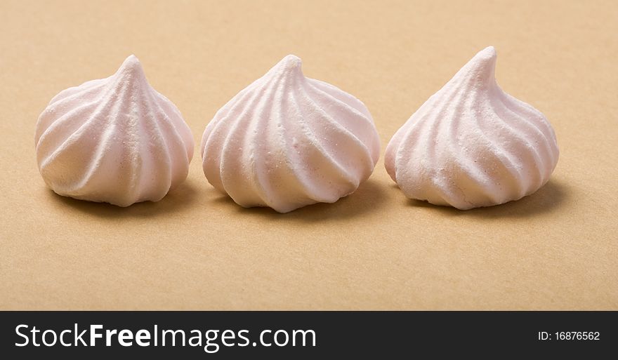 Three Pink Merinque cakes on the cardboard background.