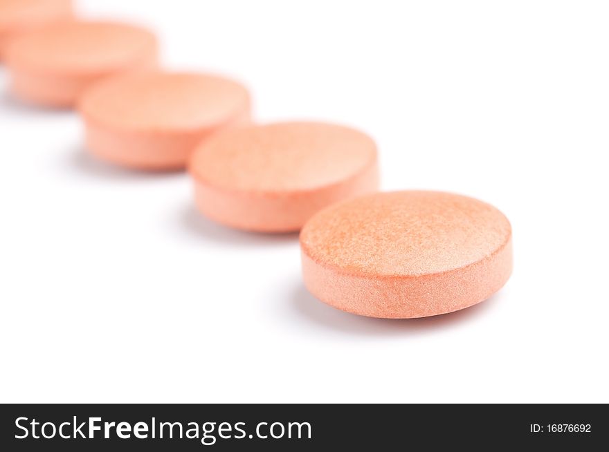 Close-up of orange pills row, isolated on white, selective focus. Close-up of orange pills row, isolated on white, selective focus