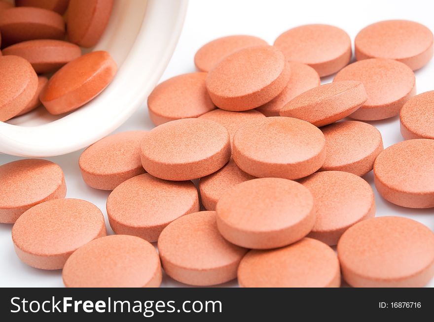 Close-up of orange pills with bottle, isolated on white, selective focus. Close-up of orange pills with bottle, isolated on white, selective focus.