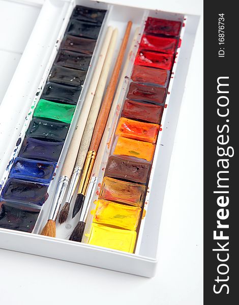 A pack of watercolour paints with brushes on a white background