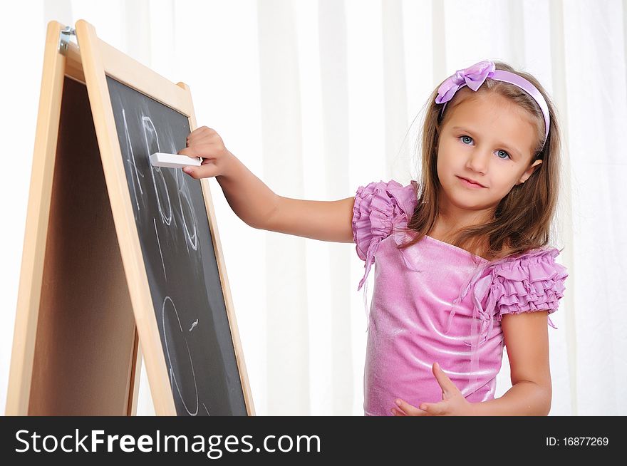 A little girl wrote in chalk on the graphite board. Receive their education.