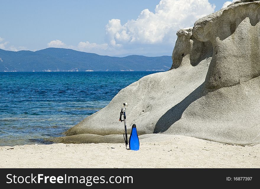 Sea rocks with a fishing gaff and swim fins at Kakoudia beach near the city of Ierissos in Chalkidiki North Greece. Sea rocks with a fishing gaff and swim fins at Kakoudia beach near the city of Ierissos in Chalkidiki North Greece