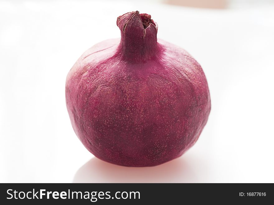 Fresh whole pomegranate on white table.