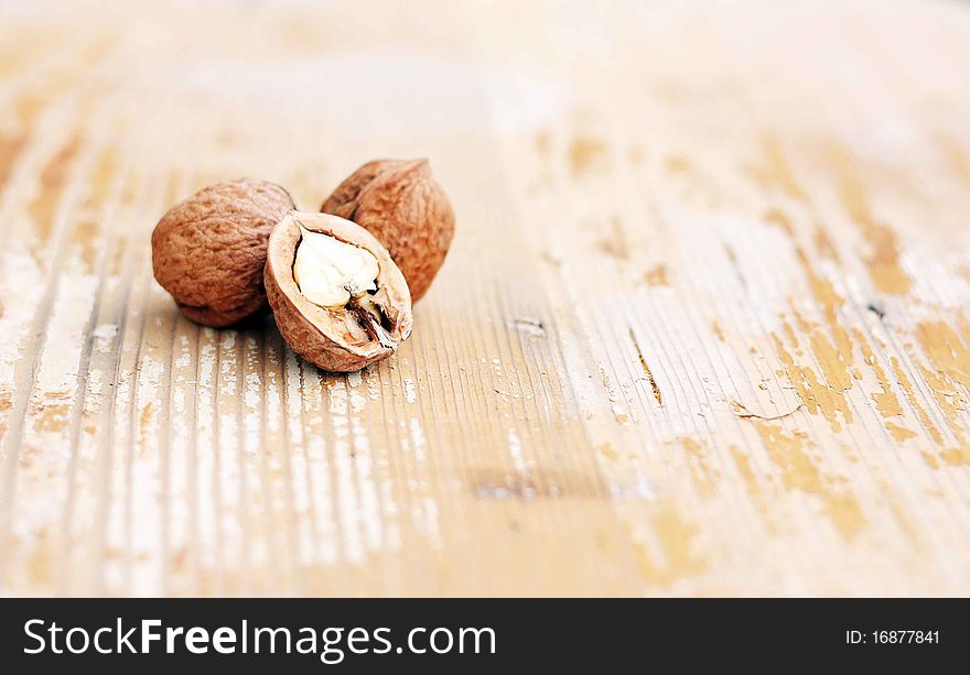Three walnuts are two whole and one halved on wooden backgroun