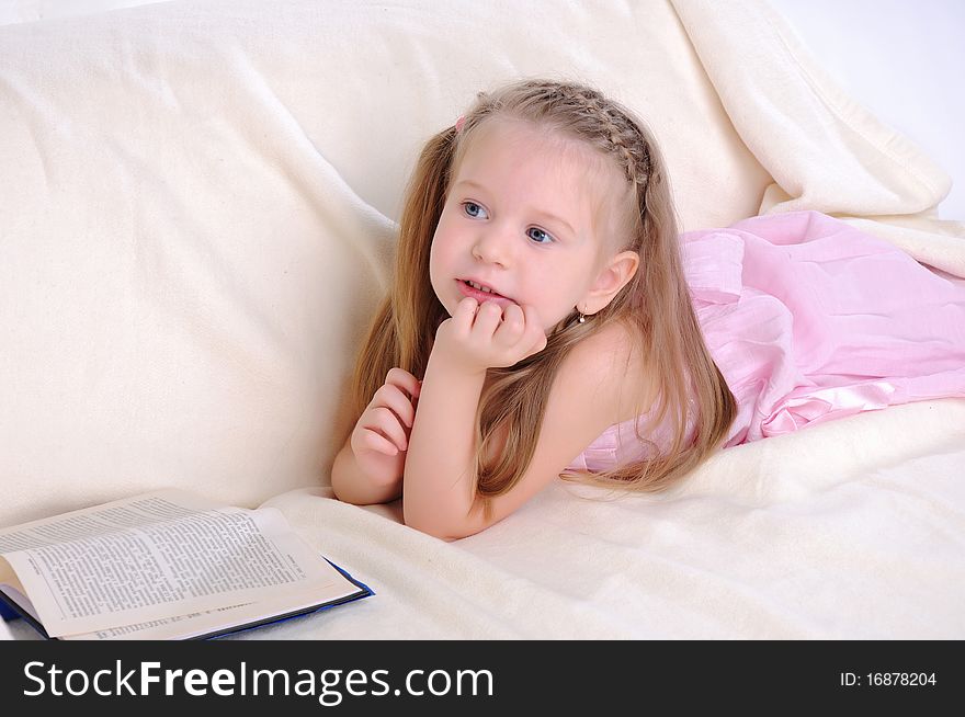 Little girl lying on the couch reading a book