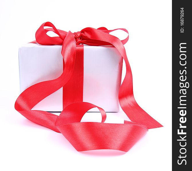 Gift in silver wrapping with a red bow on white background