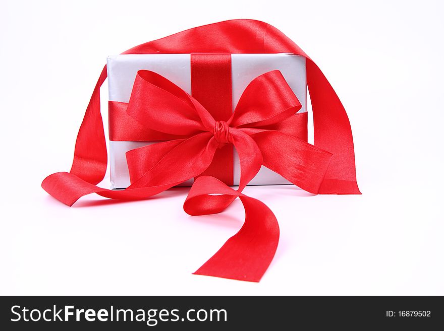 Gift in silver wrapping with a red bow on white background