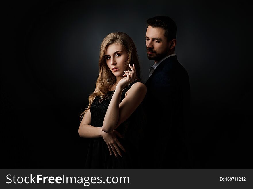 Elegant couple on black background. handsome men and beautiful women in black dress