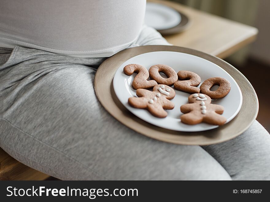 close up. Cropped photo of pregnant woman holding number 2020 of ginger cookies on belly. people and expectation concept. Happy motherhood, healthy life. expecting a child. Baby born in 2020 copyspace