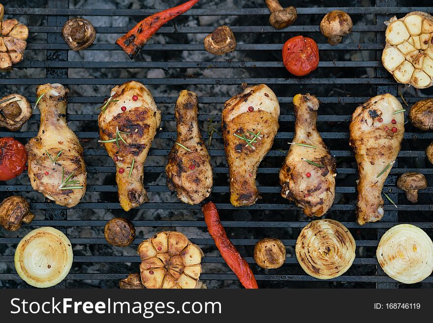 Closeup of a barbecue grill with chicken legs and vegetables