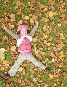 Little Girl At Grass And Leafs In The Park. Royalty Free Stock Image