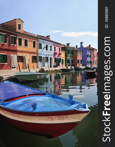 Colorful houses of Burano with a bright-colored boat in the foreground. Colorful houses of Burano with a bright-colored boat in the foreground
