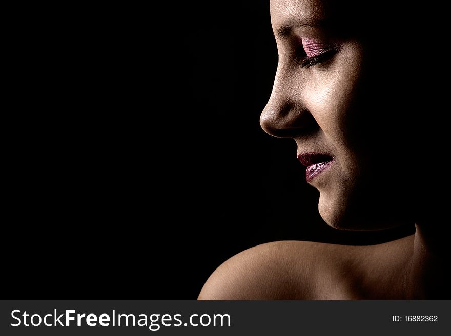High contrast, closed eyes , head and one bare shoulder portrait of a young Indian female in dark background. High contrast, closed eyes , head and one bare shoulder portrait of a young Indian female in dark background