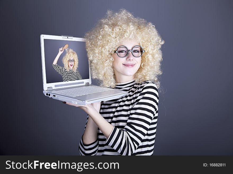 Portrait of funny girl in blonde wig with laptop