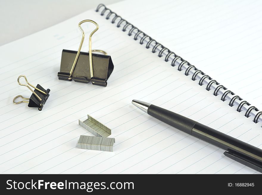 Empty spiral notebook with paper clip, pencil and