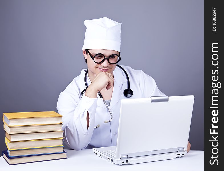 Young doctor with books and computer. Studio shot.