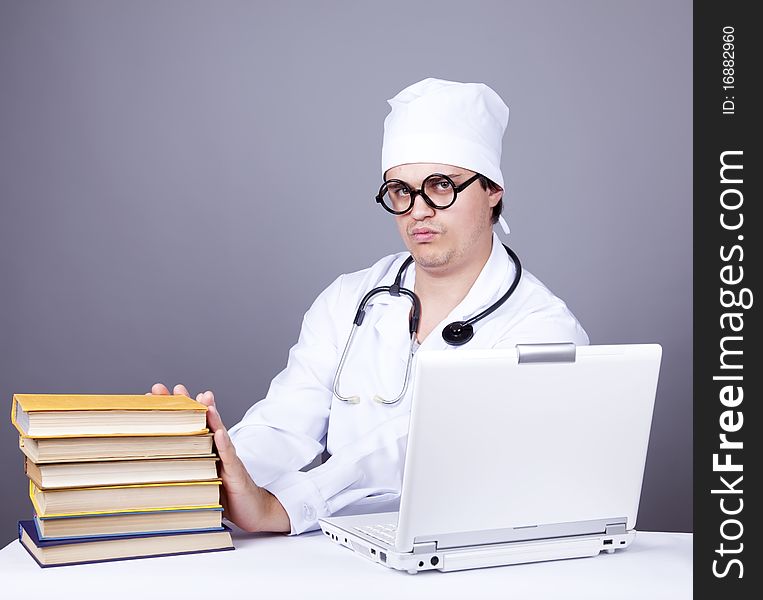 Young doctor with books and computer. Studio shot.